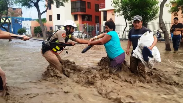 Policía ayuda a pobladores a cruzar el huaico. Foto referencial: Andina