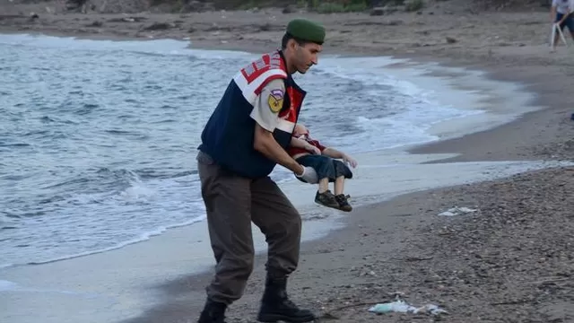 Un oficial levanta el cuerpo de Aylan Kurdi del mar en el centro tur&iacute;stico de Bordrum. (V&iacute;a: The Mirror)