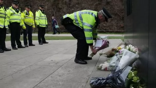Un policía deja flores en el lugar donde fallecieron las víctimas. (Vía: Twitter)
