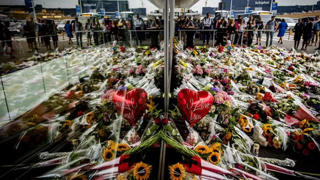 La gente mira a las flores que han sido dejadas en recuerdo de las víctimas del choque del vuelo MH17 en el aeropuerto Schiphol, Amsterdan. (Foto: AFP)