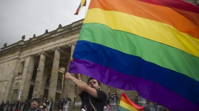 Activista gay alza una bandera del orgullo. (Vía: AFP)