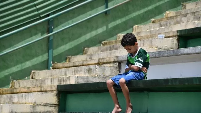 Un niño se sienta solo durante un tributo a los jugadores del equipo brasilero Chapecoense. (Vía: AFP)