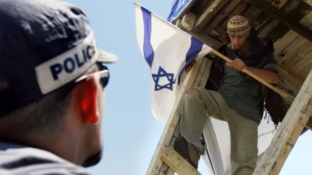 Un polic&iacute;a israel&iacute; le pide a un colono jud&iacute;o que descienda de una torre en Territorios Ocupados. (V&iacute;a: AFP)