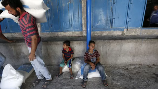 Palestinos se sientan y caminan fuera de un centro de distribuci&oacute;n de ayuda de la Agencia de Obras P&uacute;blicas y Socorro de las Naciones Unidas (UNRWA). (Foto: AFP)