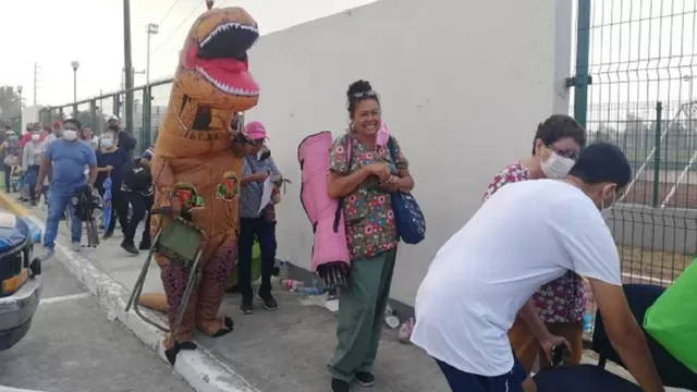 Facebook: Hombre disfrazado de dinosaurio acompaña a su madre a ponerse la vacuna contra COVID-19. Foto: Milenio